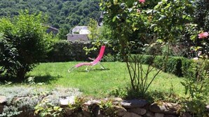 Ein Garten mit einer Steinsmauer, einem roten Stuhl und einem Baum mit rosa Blüten.