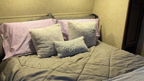 Una cama con cubrecolcha acolchado, dos almohadas y una manta.