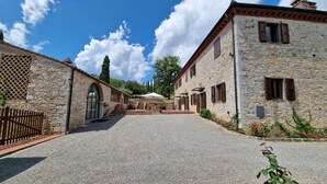 Un bâtiment en pierre avec une cour recouverte de gravier, des fenêtres en arc de cercle et une clôture en bois.