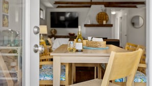 A dining area with a wooden table, chairs, and a bottle of wine.
