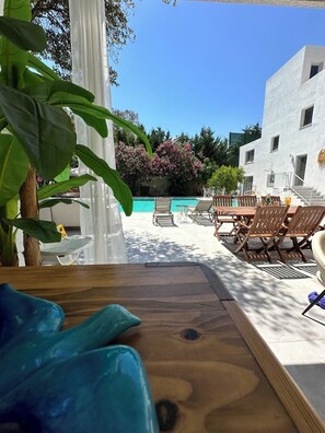 A poolside area with a wooden deck, lounge chairs, and a white building in the background. - Mumu Bodrum Hotel (Bodrum)