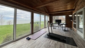 Habitación amplia con ventanas grandes que dan a un espacio verde y una masa de agua.