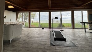 Una habitación amplia con ventanas grandes, una cinta de correr y un diseño minimalista.