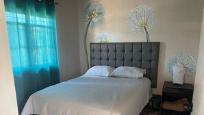 Ein Schlafzimmer mit einem Bett, einem Nachttisch und Wandbildern.