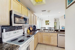 A kitchen with a stove, microwave, and dishwasher. - Colorful condo walkable to the beach with pool, balcony, central AC, & W/D (South Padre Island)