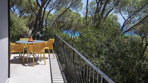 A balcony with a round table and chairs, surrounded by trees and a railing. - Villa Opuntia - Sirens Avenue (Pula)