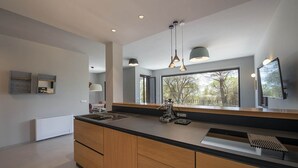A modern kitchen with a large island, pendant lighting, and a view through the window. - Villa Opuntia - Sirens Avenue (Pula)
