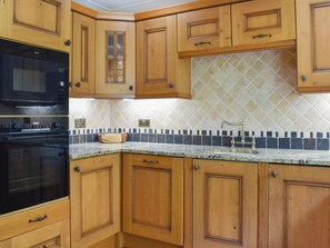 Una cocina con armarios de madera, un microondas negro y un salpicadero de azulejos.