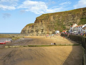 Une plage côtière avec une rive sablonneuse, une falaise et une rangée de bâtiments le long de la promenade.