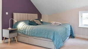 Een slaapkamer met een bed, nachtkastje, lamp en een raam.