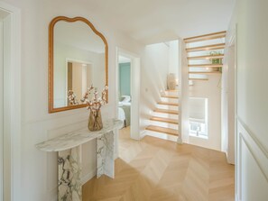 A hallway with a marble console table, a large mirror, and a staircase with wooden steps.