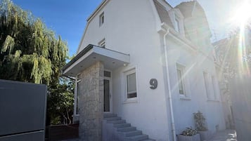A two-story house with a stone facade, a number '9' on the front, and a paved driveway leading to the entrance.