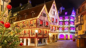 A traditional European street with half-timbered buildings adorned with festive lights and decorations.