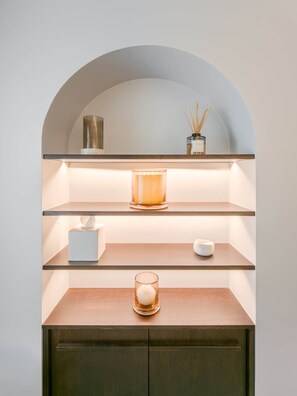 A minimalist shelf with a candle, a diffuser, and a small container.