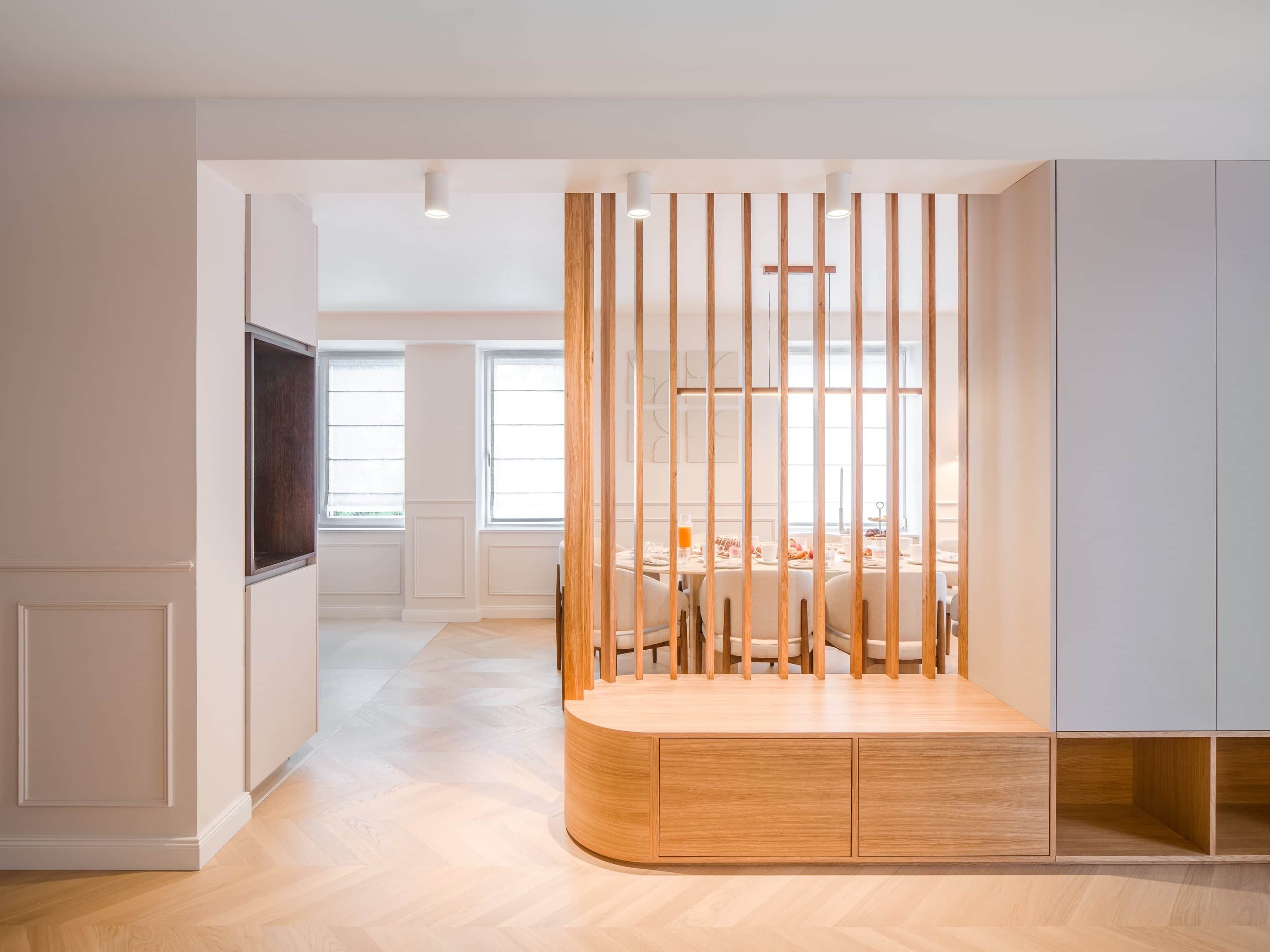 A modern interior with a dining area, wooden partition, and built-in cabinets.