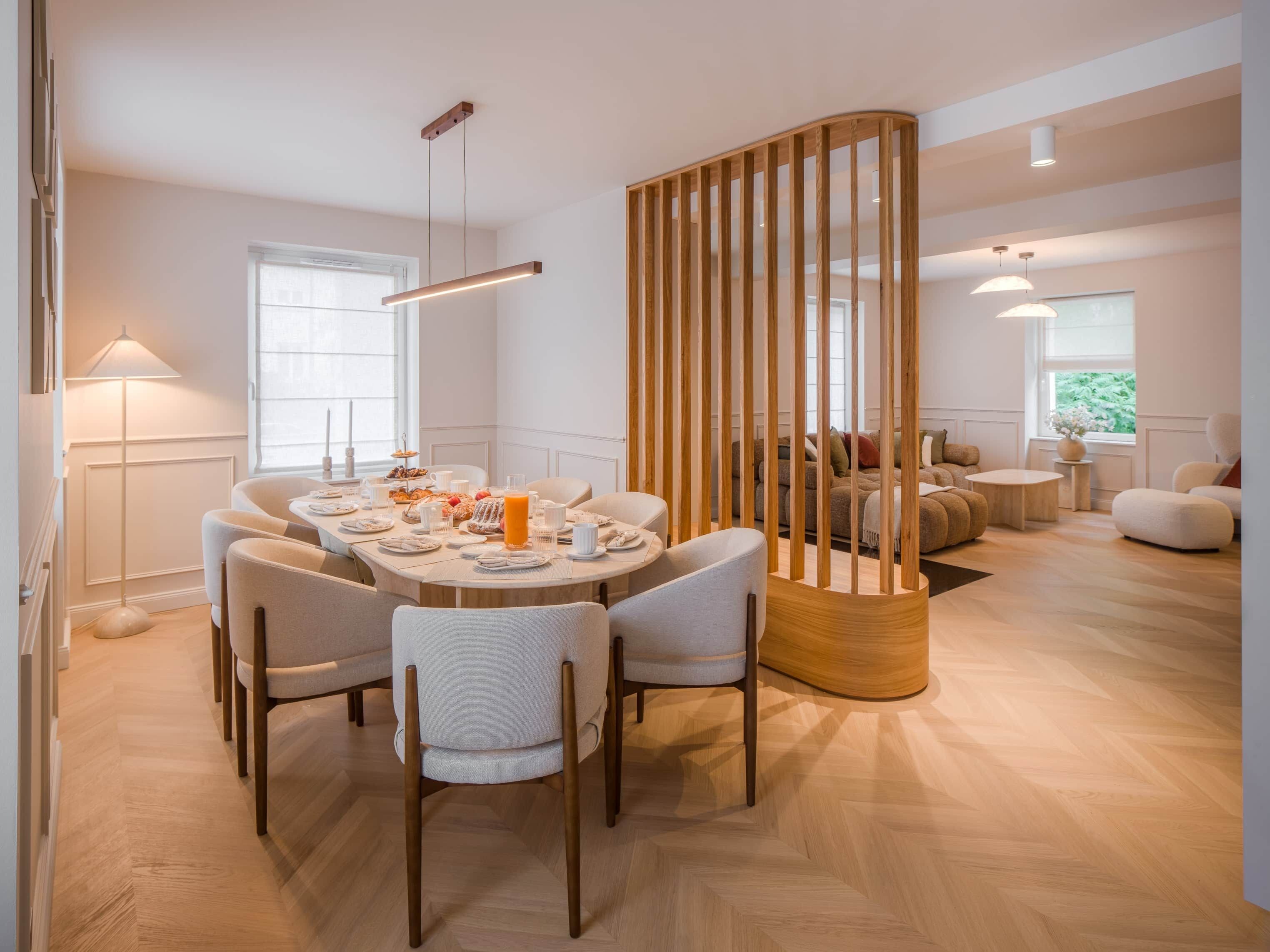 Zona pranzo moderna con tavolo rotondo, sedie e un divisorio in legno.