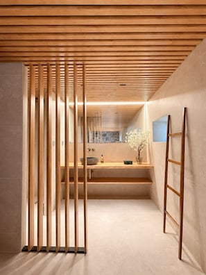 A modern bathroom with a wooden slatted partition, a stone sink, and a mirror.