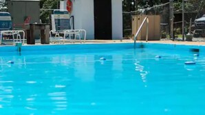 Una piscina con agua azul cristalina, un trampolín y un puesto de socorrista.