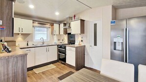 A compact kitchen with a refrigerator, stove, sink, and cabinets. - 2 bedroom accommodation in Felton, near Amble (Felton, near Amble)