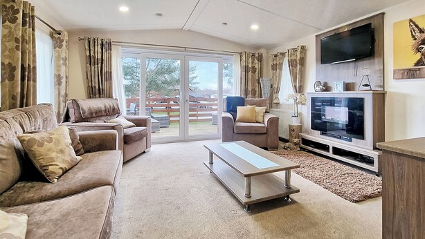 A living room with a sofa, a coffee table, a TV, and a sliding glass door leading to an outdoor area. - 2 bedroom accommodation in Felton, near Amble (Felton, near Amble)