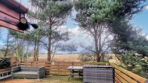 A patio area with a wooden fence, a table, and a bench. - 2 bedroom accommodation in Felton, near Amble (Felton, near Amble)