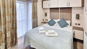 A hotel room with a bed, curtains, a nightstand, and a cabinet. - 2 bedroom accommodation in Felton, near Amble (Felton, near Amble)