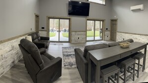 Amplia sala de estar con un televisor grande, asientos cómodos y vistas al exterior.