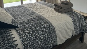 Un dormitorio con una cama grande, vistas a un patio con mobiliario exterior y una puerta de madera.