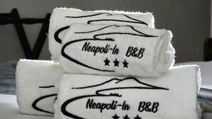 Tres toallas dobladas con pulcritud con el texto "Neapoli-in B&B" y tres estrellas.