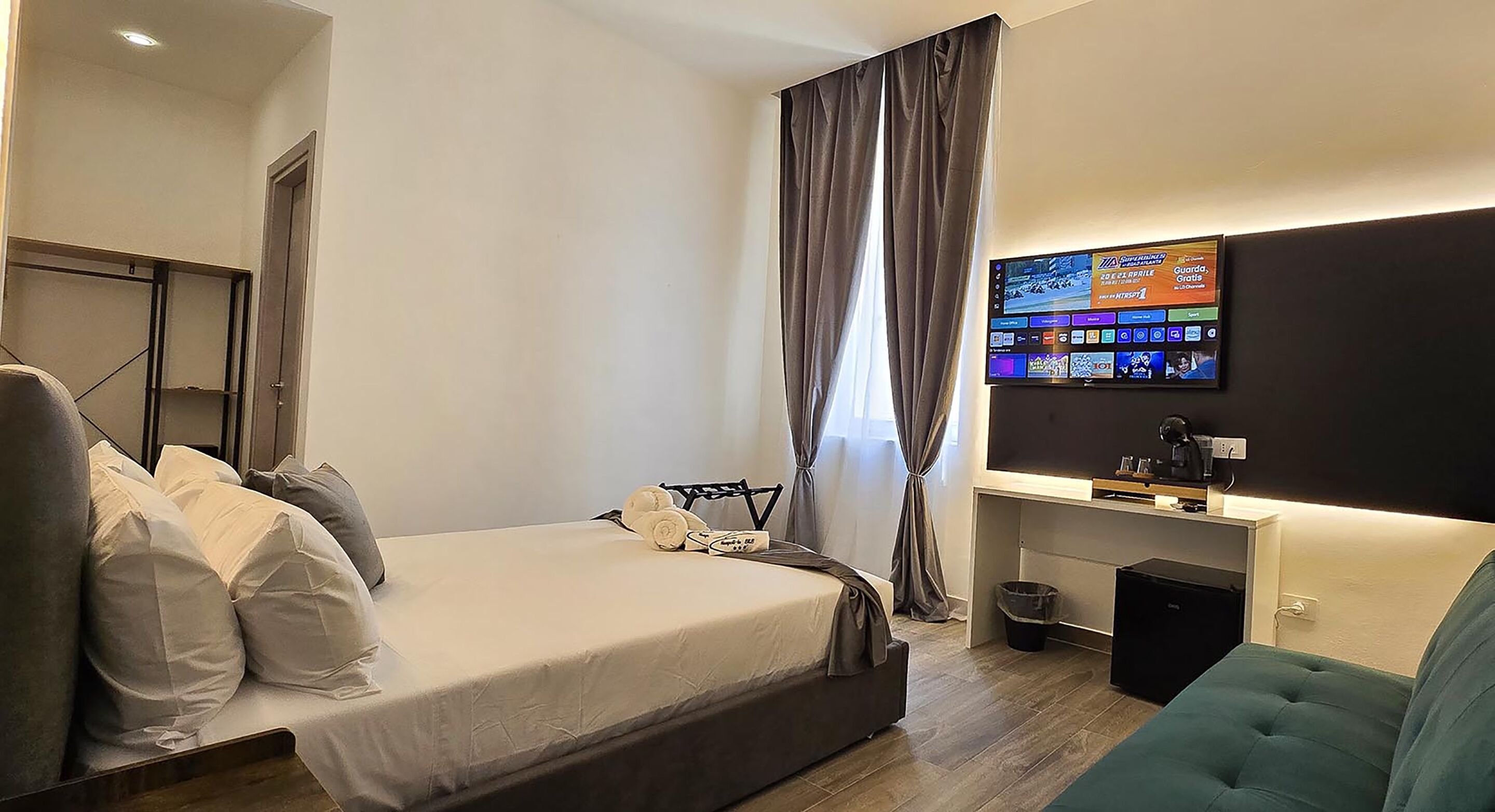 Ein modernes Hotelzimmer mit Bett, Schreibtisch, Fernseher und einem kleinen Mülleimer.