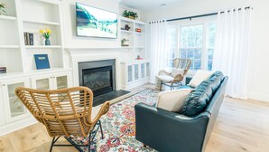 A living room with a fireplace, a television, a sofa, and a chair. - Claire's Charming Home near RDU and RTP (Raleigh)