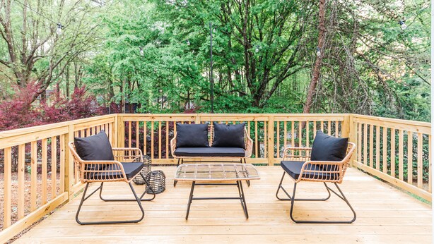 A wooden deck with wicker furniture and a cushioned bench. - Claire's Charming Home near RDU and RTP (Raleigh)