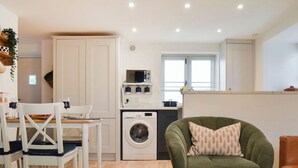 A compact living space with a dining area, a washing machine, a microwave, and a green armchair. - 3 bedroom accommodation in Easington, near Staithes (Easington, near Staithes)