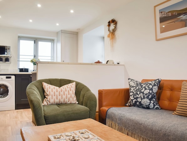 A modern living room with a green armchair, an orange sofa, and a wooden coffee table.