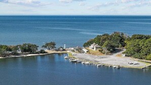 A marina with boats docked, a lighthouse, and a building with a large driveway. - Garber Harbor in Colington Harbor Waterfront Canal  Hot Tub Jimmy Buffett Bar  (Kill Devil Hills)