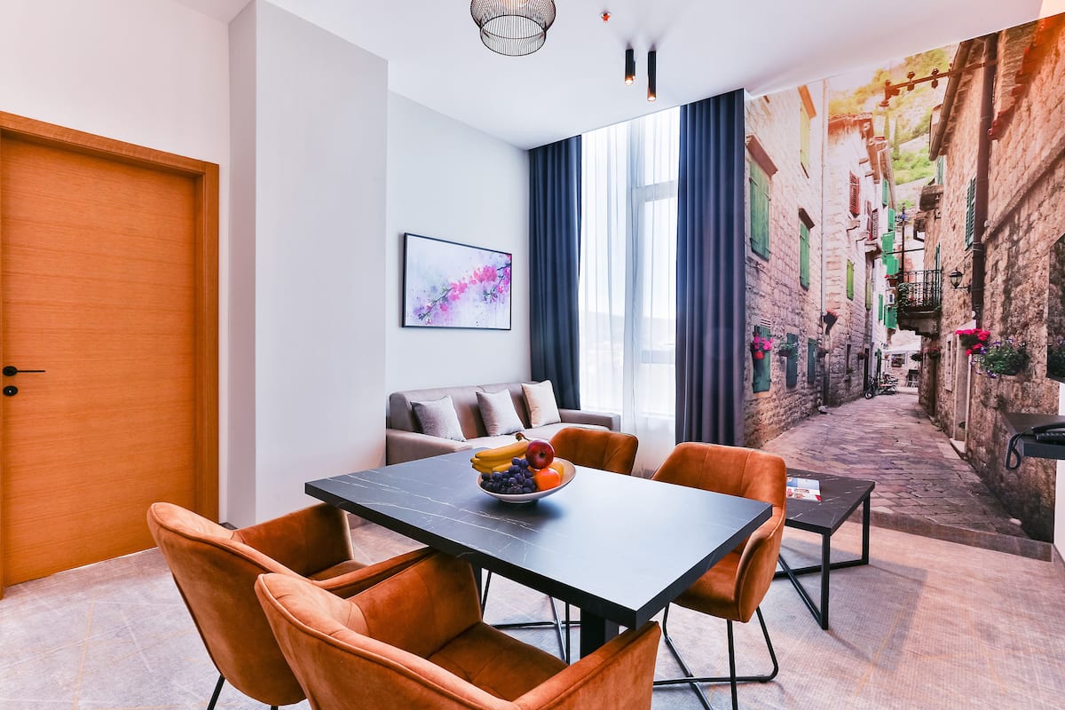 A modern dining area with a table, chairs, and a fruit bowl.