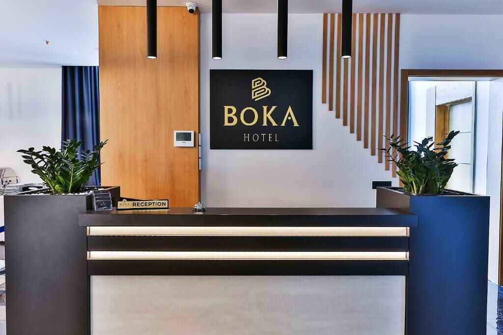 A reception desk with a sign reading "BOKA HOTEL" and a "RECEPTION" sign on top.