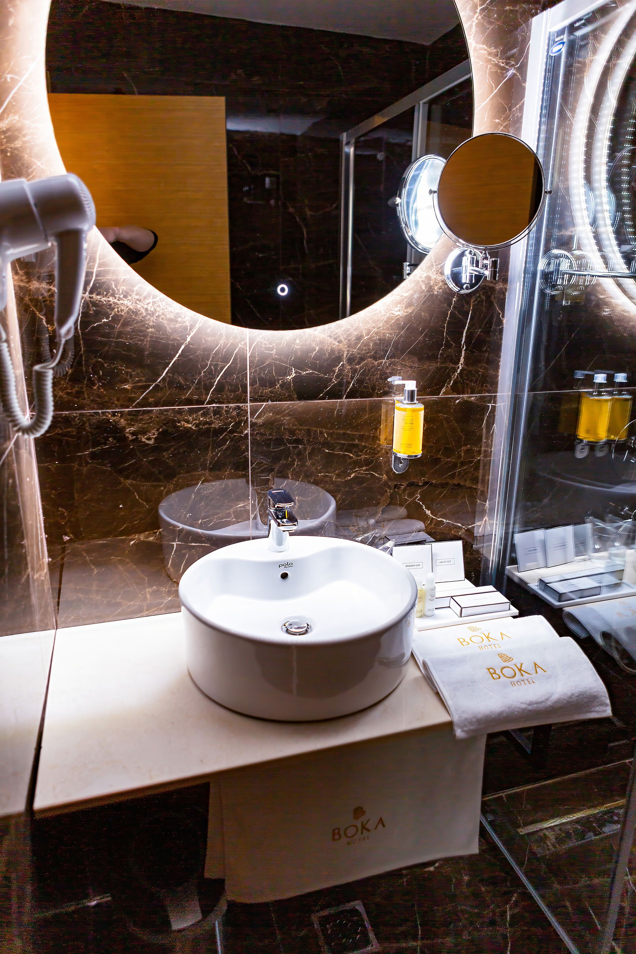 Un bagno con un lavandino bianco, uno specchio e articoli da toilette sul ripiano.