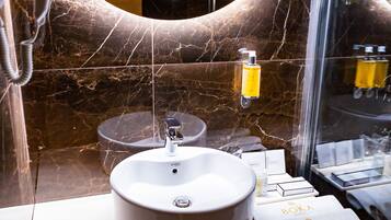 Un bagno con un lavandino bianco, uno specchio e articoli da toilette sul ripiano.