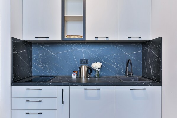 Una cocina moderna con salpicadero de mármol negro, electrodomésticos de acero inoxidable y armarios de colores claros.