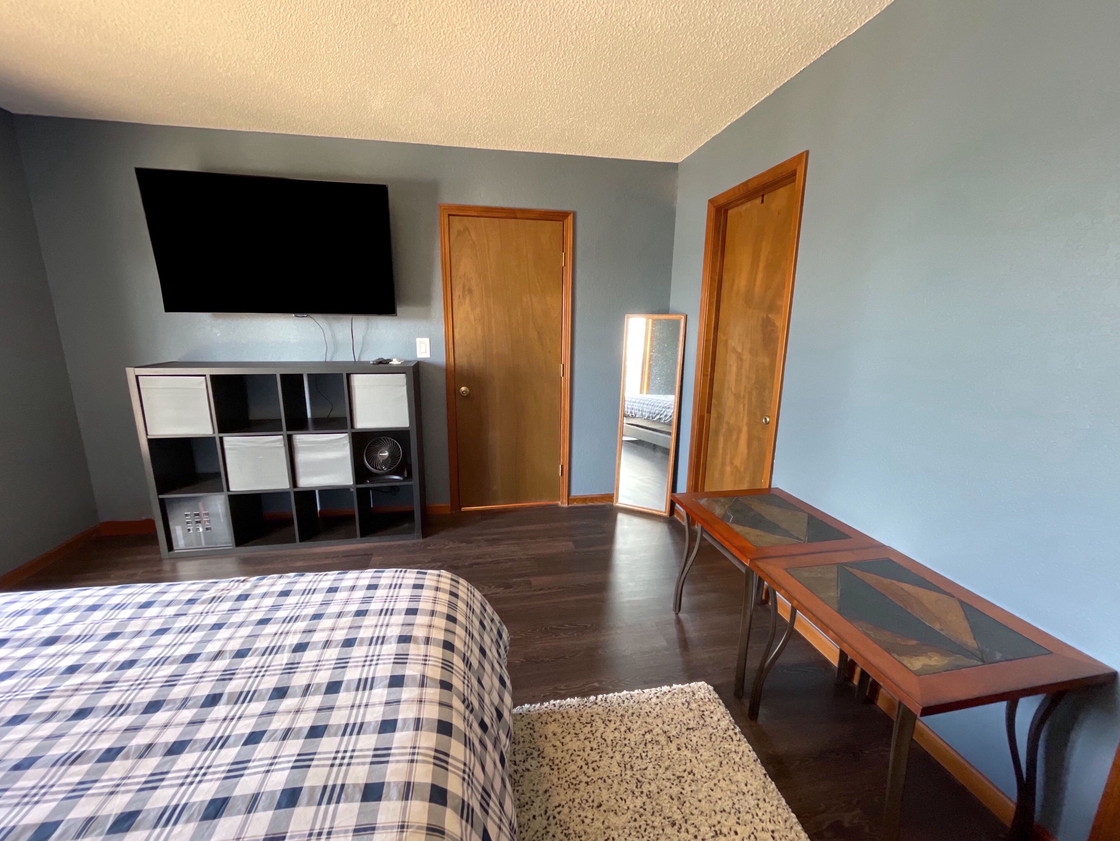 A bedroom with a bed, a TV, a dresser, and a mirror.