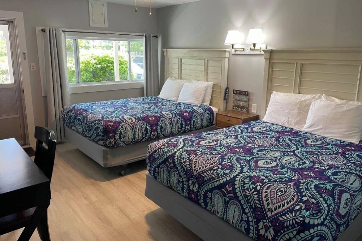 Een hotelkamer met twee bedden, een bureau en een raam met gordijnen.