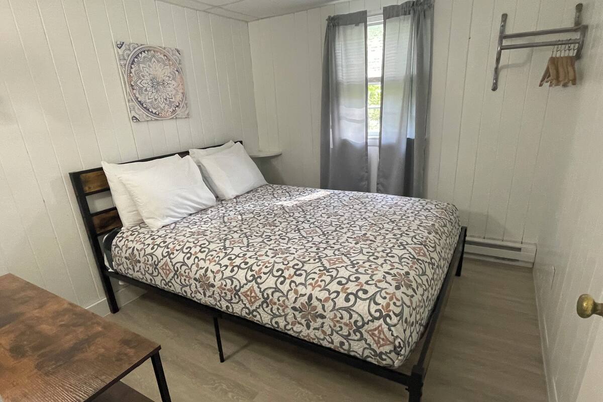 Een enkel bed met een bedovertrek met patroon, een houten hoofdbord en een nachtkastje.