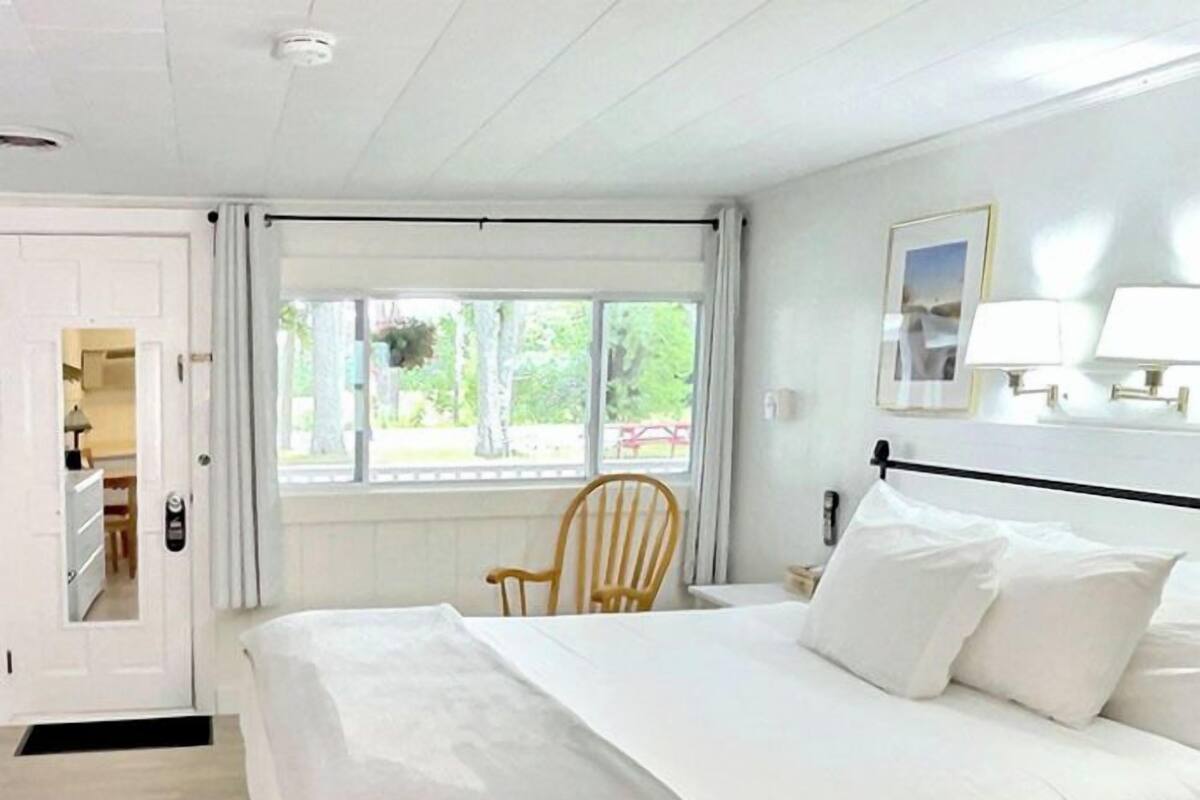 Een slaapkamer met een bed, een stoel, een raam en een deur.