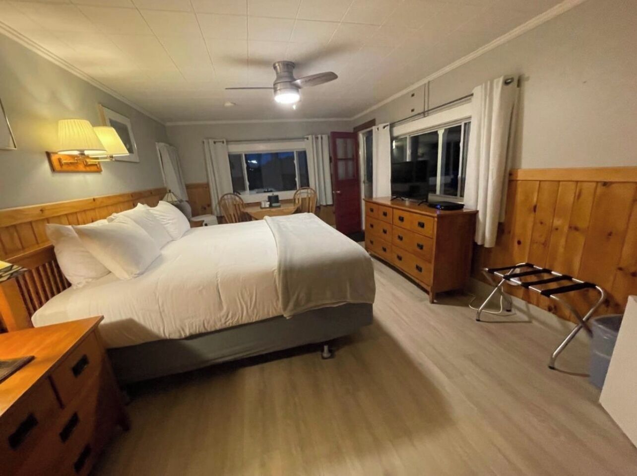 Una habitación de hotel con cama, escritorio, silla, televisión y ventana.