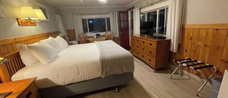 Una habitación de hotel con cama, escritorio, silla, televisión y ventana.
