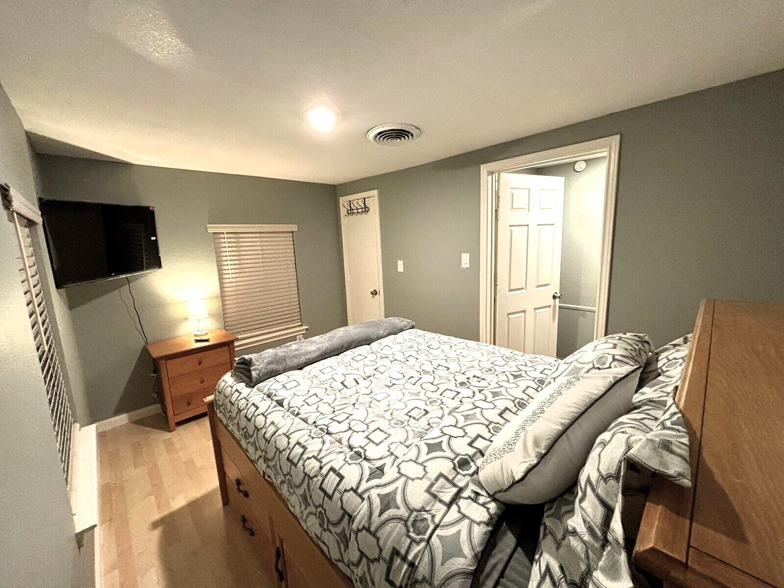 A bedroom with a bed, bedside table, and a TV mounted on the wall.