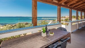 A wooden deck with a table and chairs overlooking a beach. - Stunning apartment in Privlaka with WiFi (Privlaka)