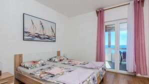 A bedroom with a bed, a nightstand, a painting, and a view of the sea through a glass door. - Stunning apartment in Privlaka with WiFi (Privlaka)