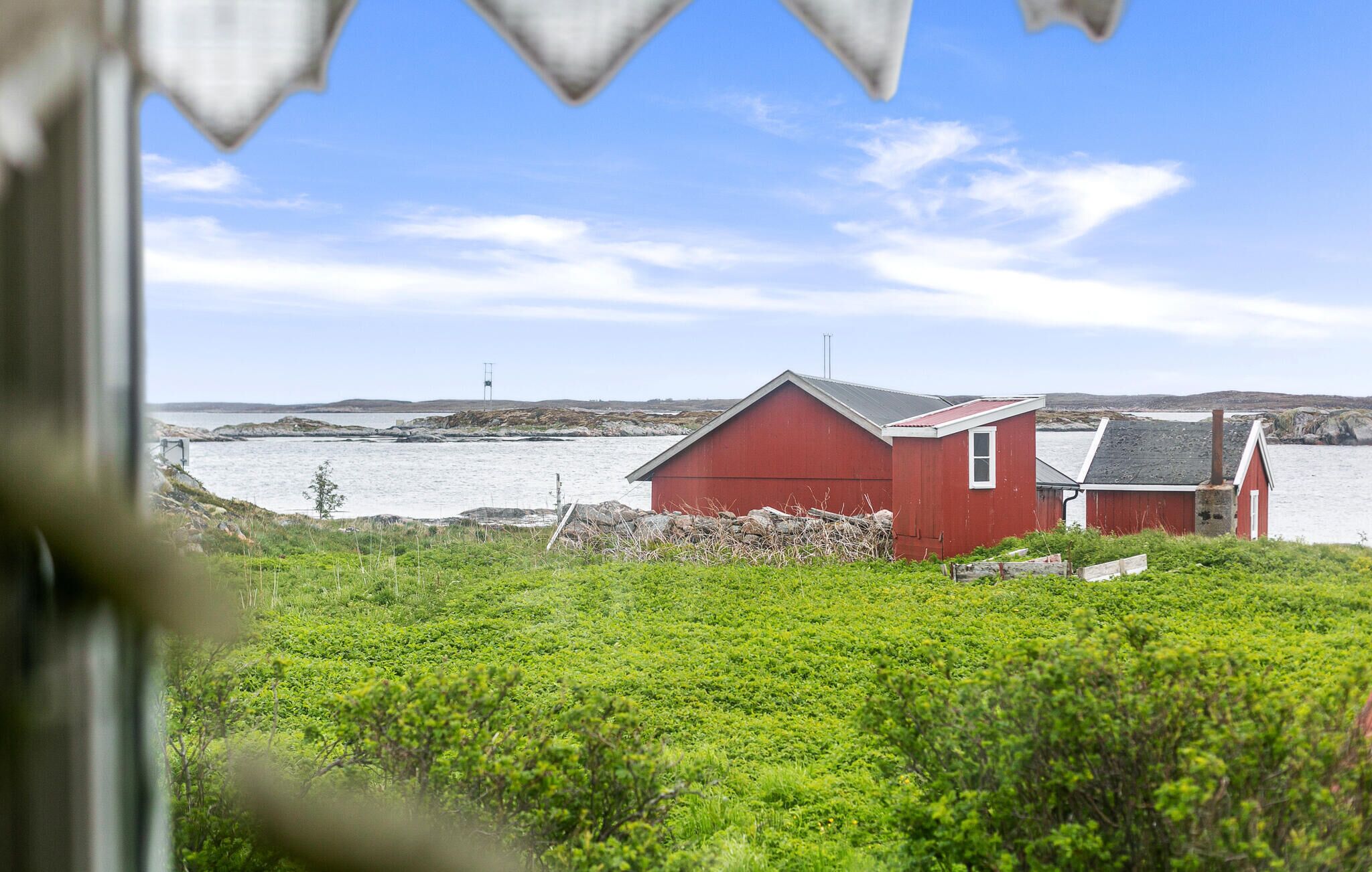 A red building near a body of water, surrounded by greenery.